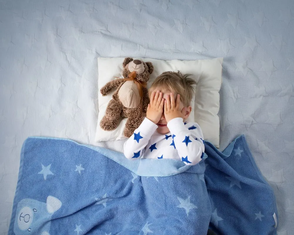4 year old in bed with his hands over his eyes