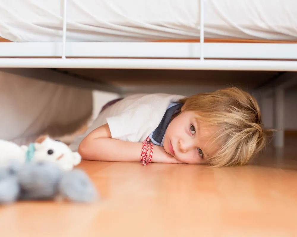 toddler laying under his bed looking for his stuffed animal