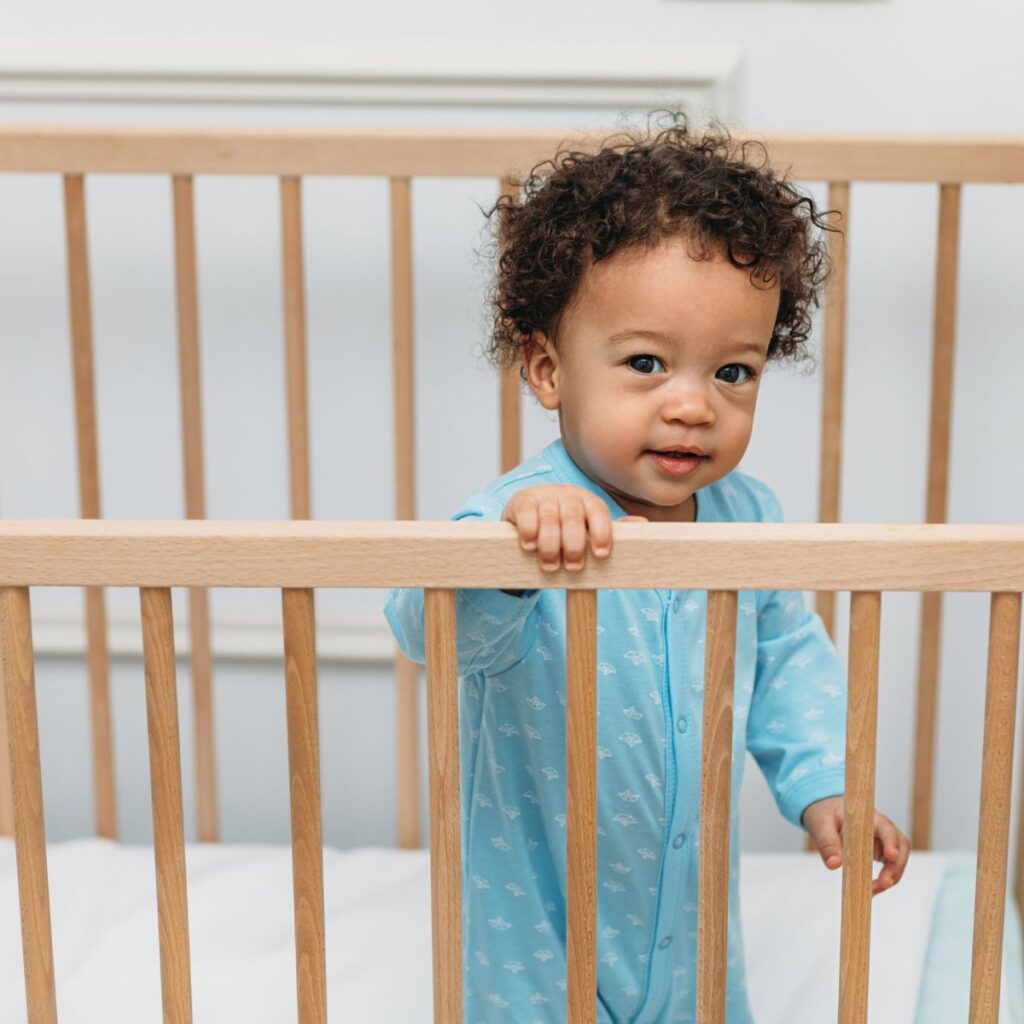 Baby standing in crib looking over rail