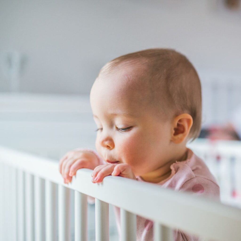 Baby standing in crib holding on to rail
