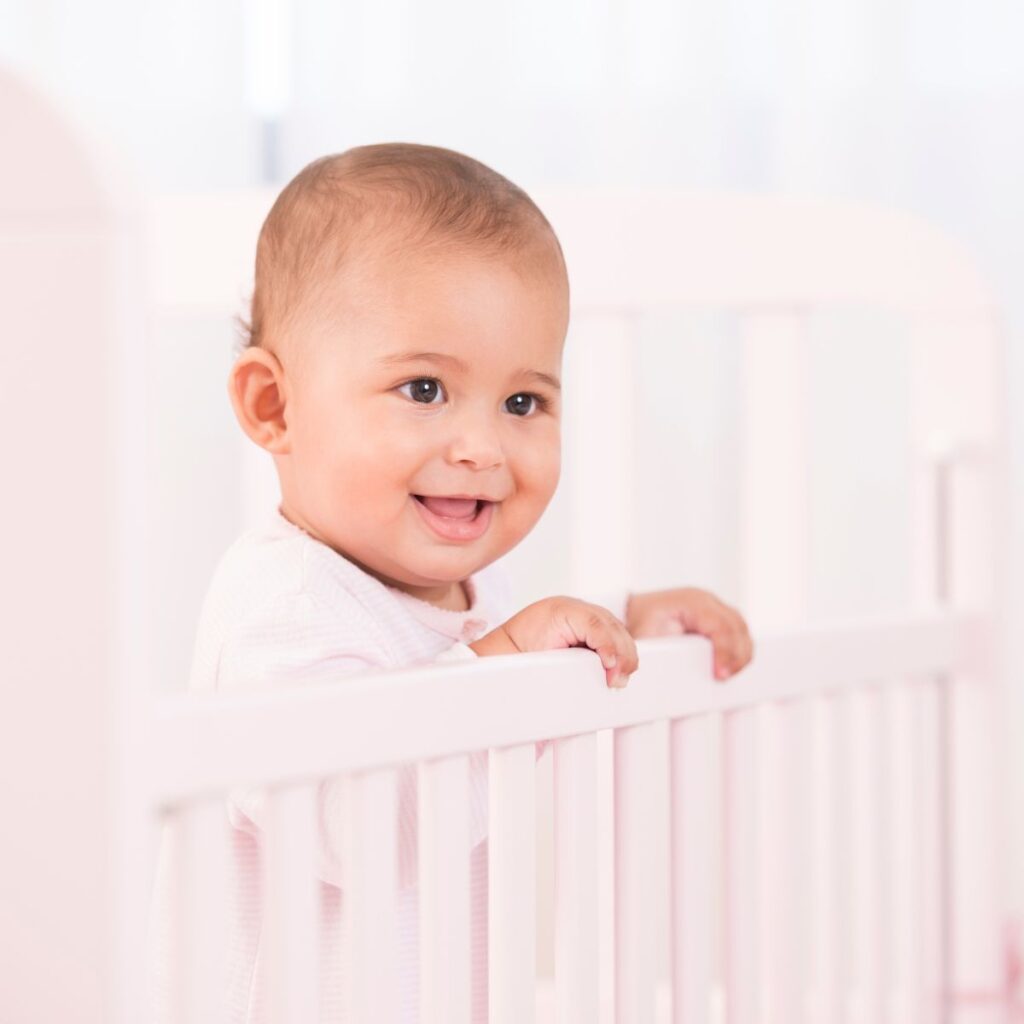 Baby smiling while standing in crib