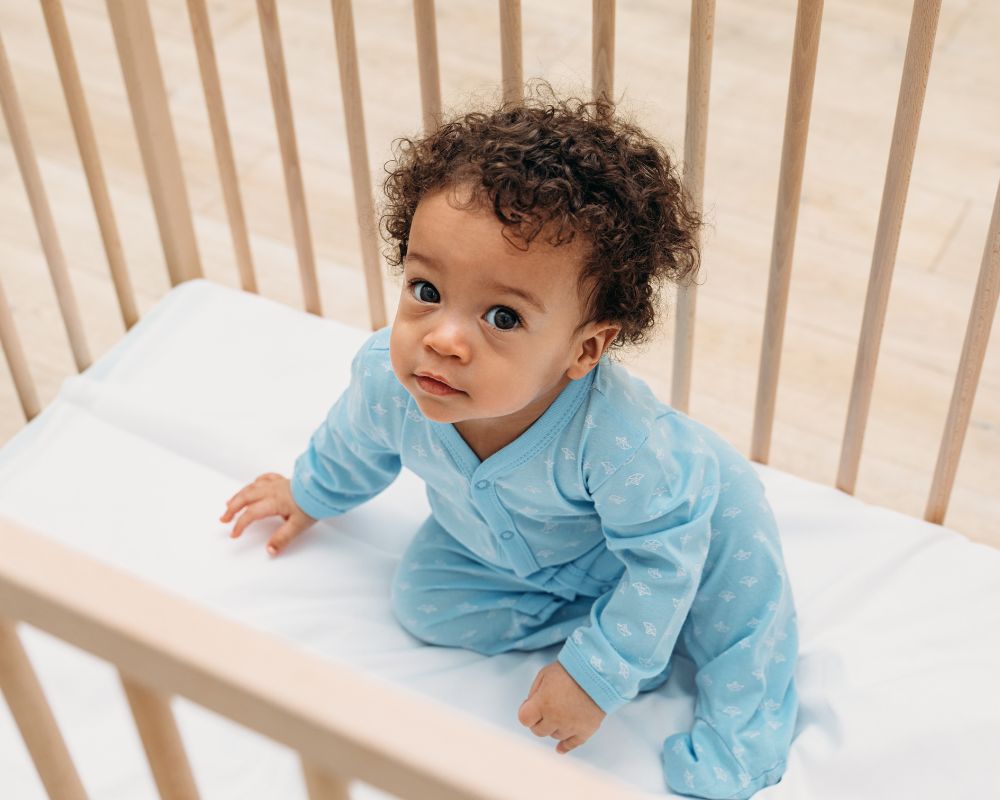 image of toddler sitting up in their crib