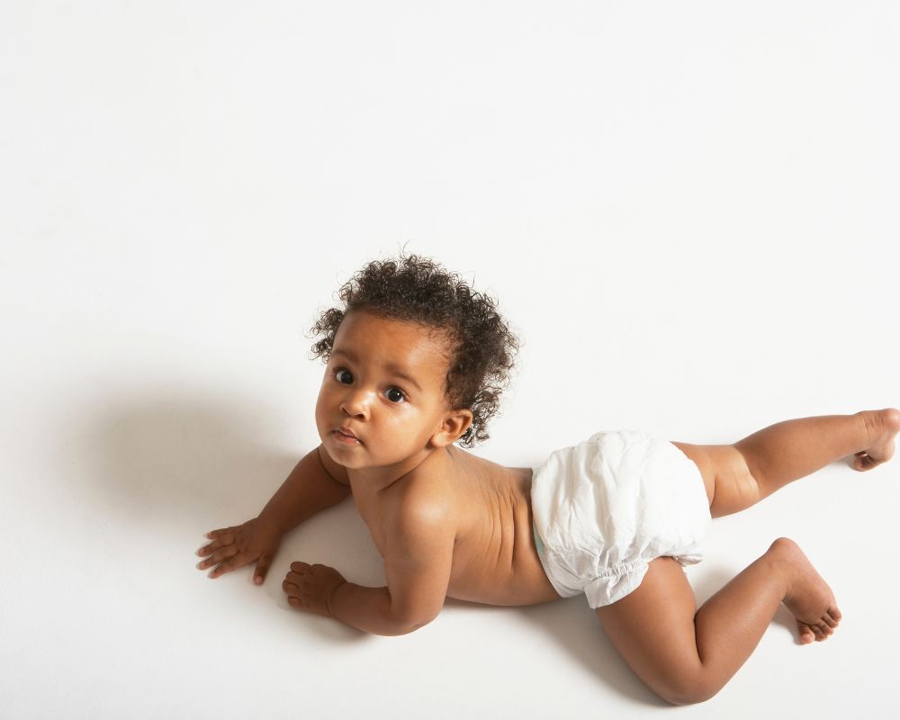 6 month old baby crawling in a diaper - physical milestones can contribute to 6 month sleep regression