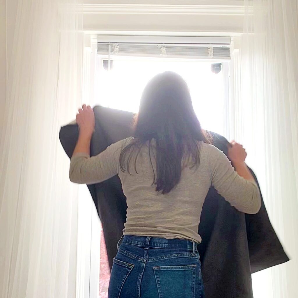 woman standing at a curtain putting up portable blackout curtain