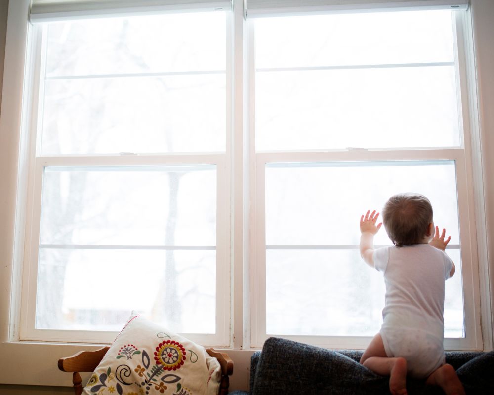image of baby leaning against a sunny window