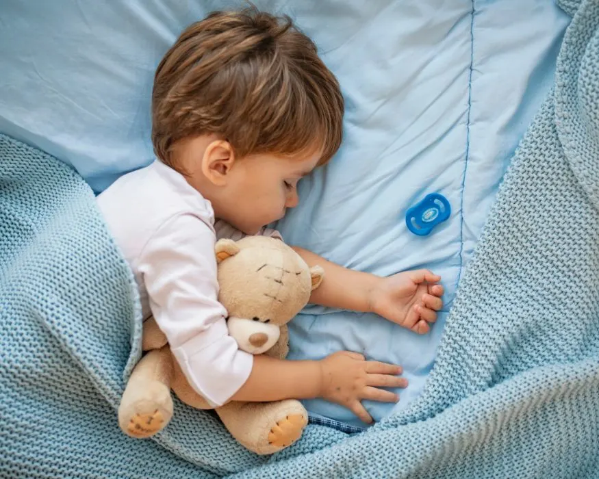 toddler sleeping with a teddy bear