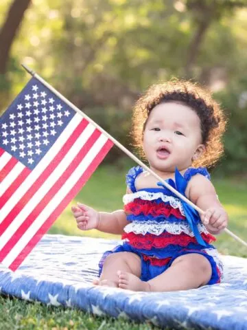 little girl dressed in 4th of July clothes holding American flag