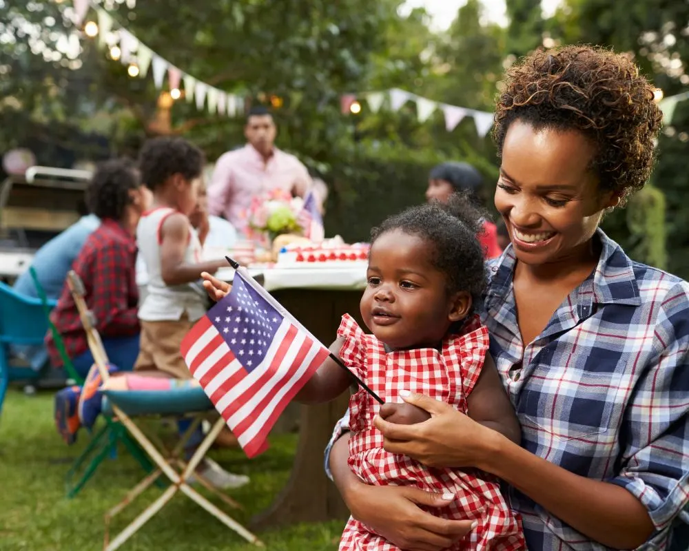 mom holding baby and the American flag at a bbq