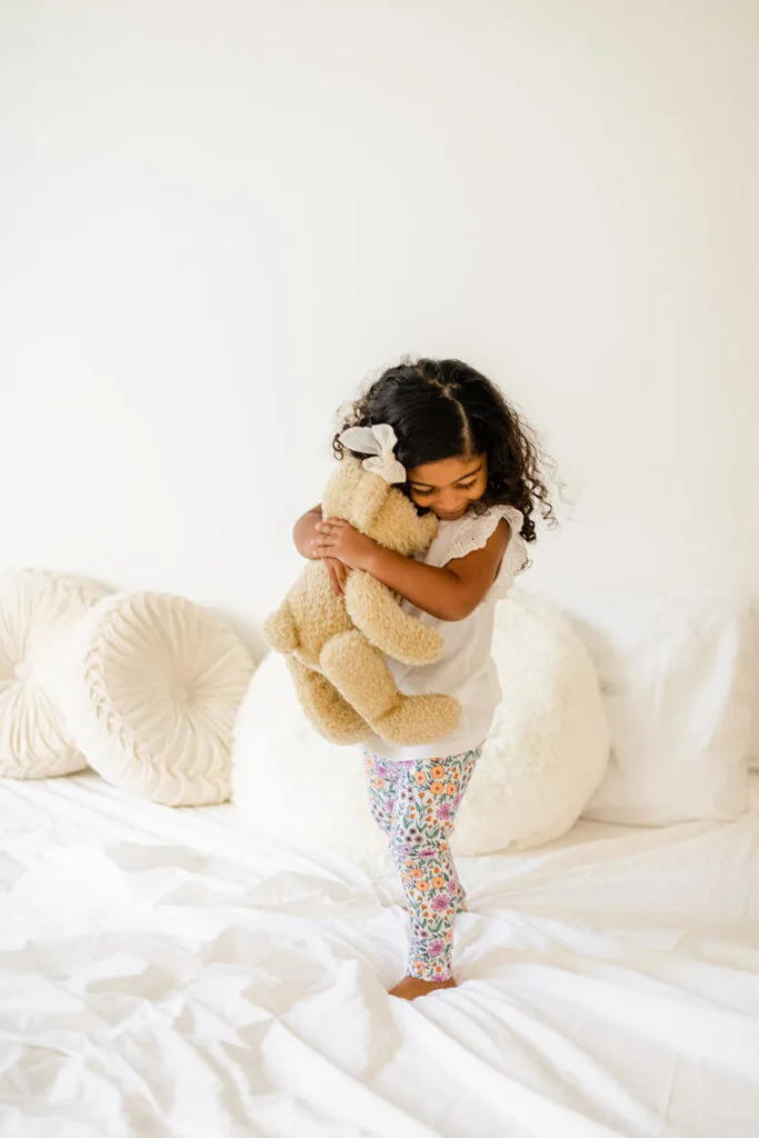 toddler girl hugging stuffie on new toddler bed