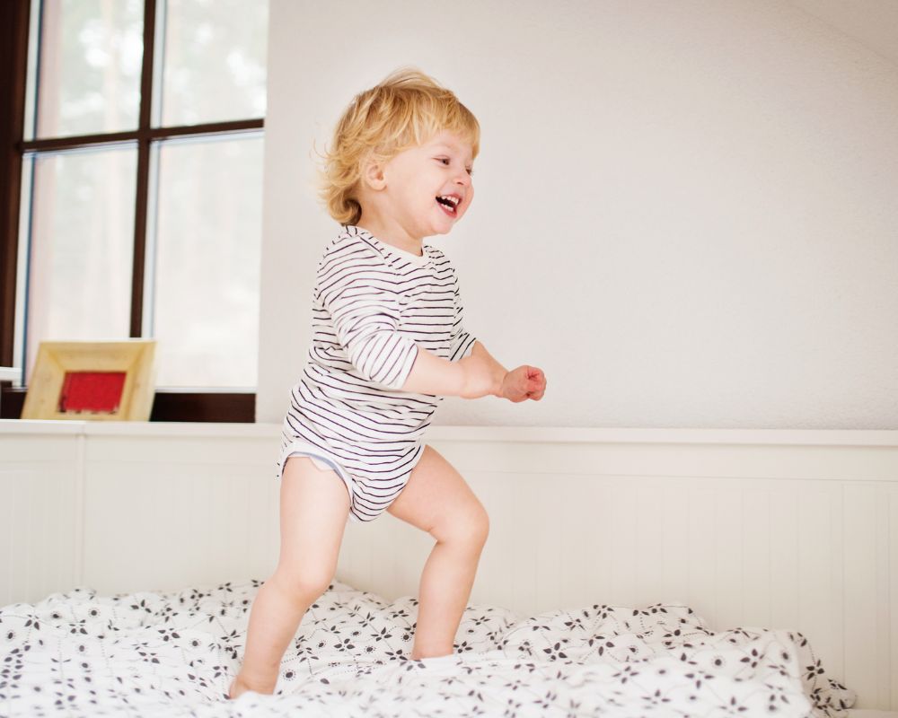 toddler playing on new bed after moving from crib