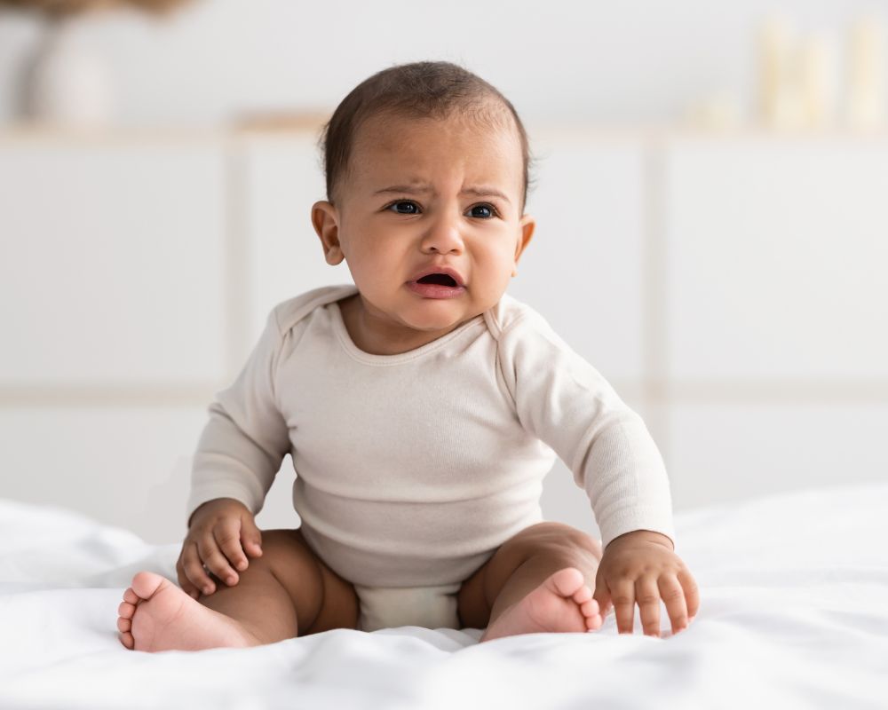 baby crying while sitting up in bed