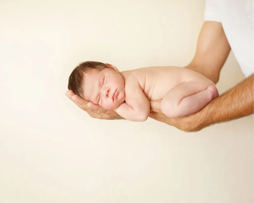 parent holding a sleeping newborn baby