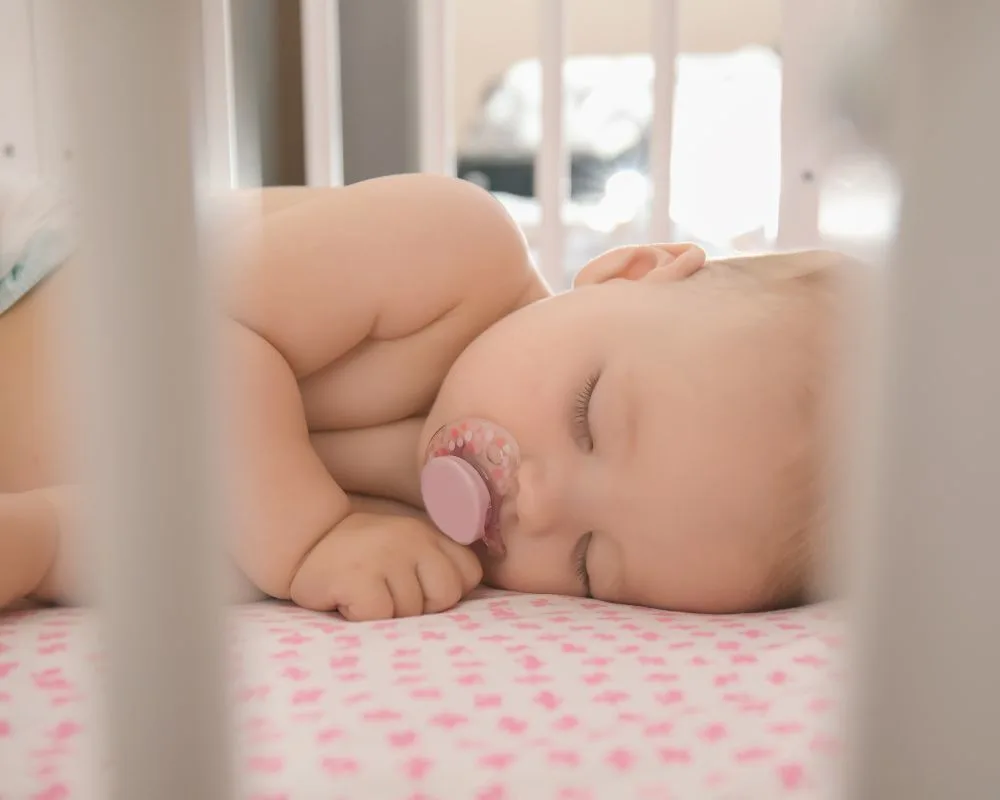 baby asleep in their crib with a pacifier