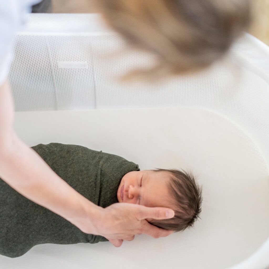 Mom comforting baby in bassinet